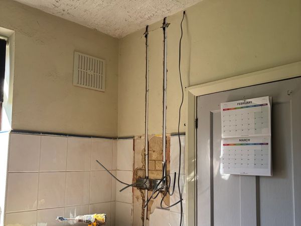 Wall with exposed wiring and calendar on the door.