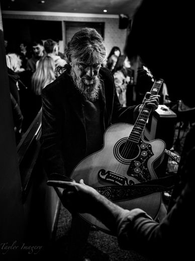 Person being handed acoustic guitar.