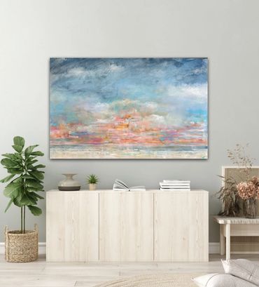 Abstract seascape painting above a light wooden cabinet in a modern living room.