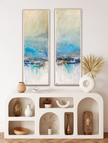 Modern white shelf with decorative vases and abstract blue paintings above.
