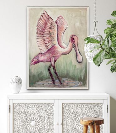 Elegant pink bird painting displayed above ornate white cabinet in a stylish room.