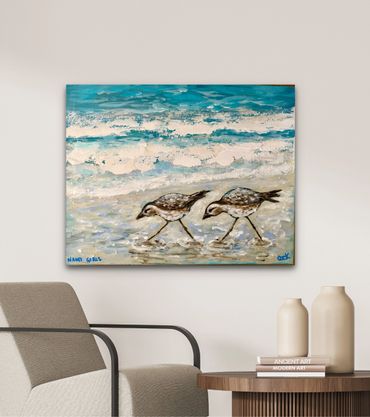 Painting of two shorebirds walking by the ocean waves.