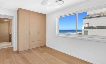 Empty modern room with wooden floor and ocean view through window.
