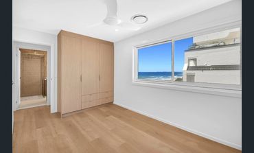 Empty modern room with wooden floor and ocean view through window.