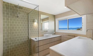 Modern bathroom with glass shower and ocean view window.