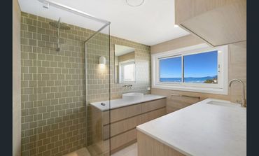 Modern bathroom with glass shower and ocean view window.