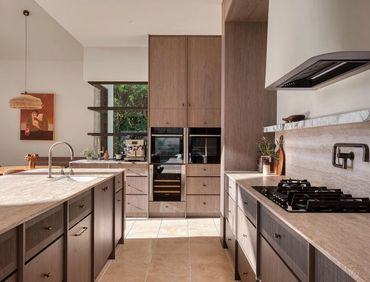 Modern kitchen with wooden cabinetry and marble countertops.