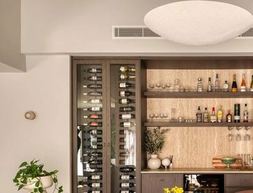Modern home bar with wine fridge and liquor shelves.