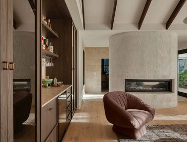 Modern living room with curved fireplace and brown armchair.
