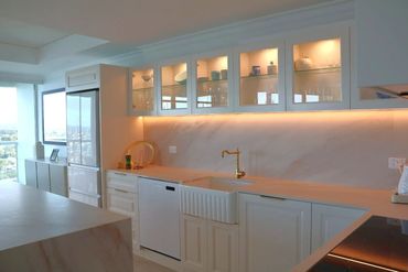 Modern kitchen with glass cabinets and warm lighting.
