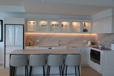 Modern kitchen with sleek white cabinets and bar stools.