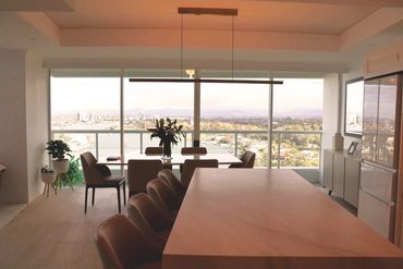 Modern dining room with large windows and scenic city view.