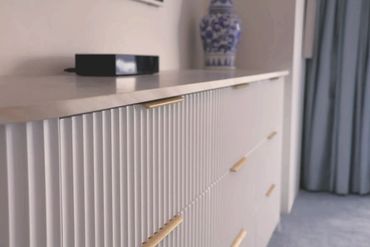 Close-up of a modern white cabinet with gold handles in a stylish room.
