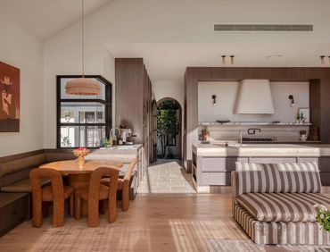 Warm, modern kitchen and dining area with natural wood tones and cozy seating.