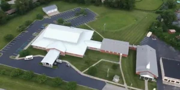 Aerial view of a large building complex surrounded by parking lots and greenery.