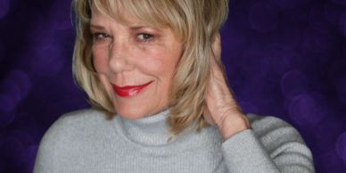 Smiling woman with blonde hair in a gray turtleneck sweater.