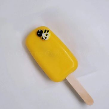 Yellow popsicle with a small bee decoration on top.