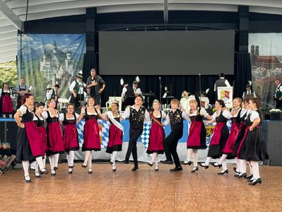 Group of dancers in traditional Bavarian attire performing on stage.