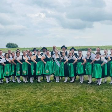 Group in traditional green and black attire posing outdoors.