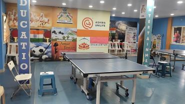 A recreational room with a ping pong table and colorful wall decor.