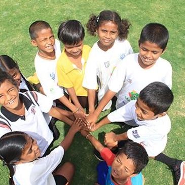 Group of children joining hands in a circle outdoors