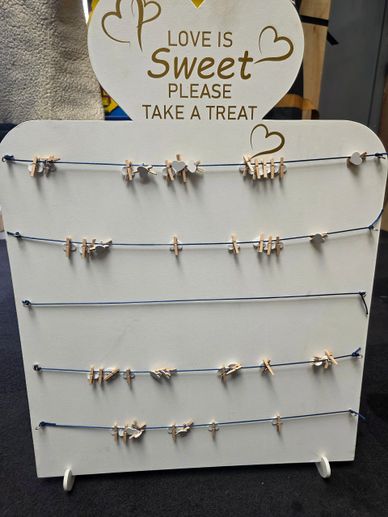 A white sign with clothespins and text inviting to take a sweet treat.