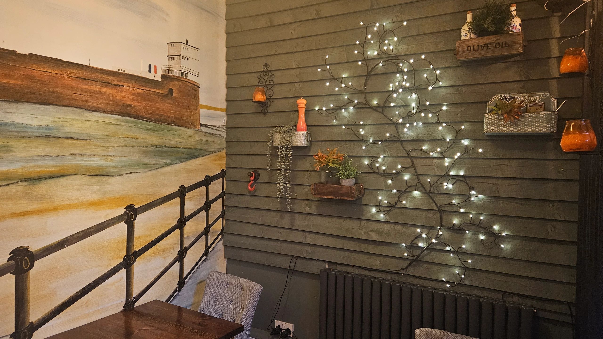 Cozy corner with fairy lights and a mural of a seaside fortress.