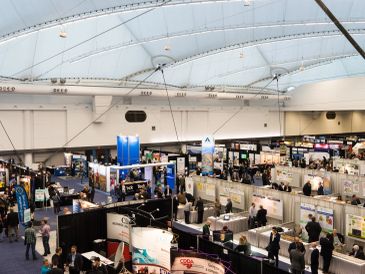 Crowded exhibition hall with multiple booths and attendees.