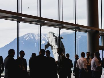 Business group conversing with mountain and whale sculpture outside.
