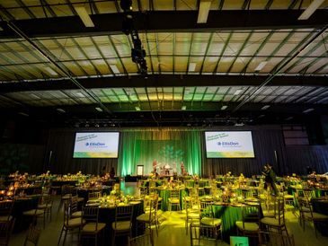 Elegant banquet setup with green lighting and stage.