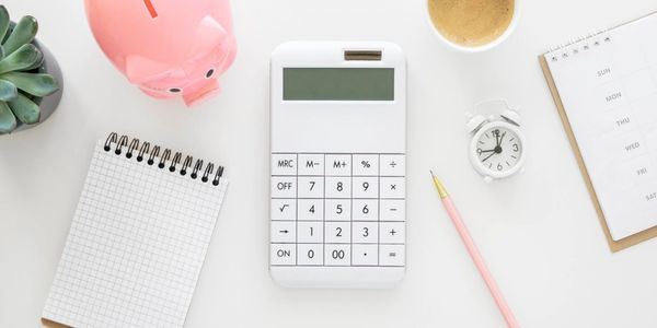 Minimal flat-lay with calculator, pink piggy bank, planner, and coffee — representing budgeting, sma