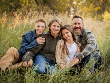 Happy family sitting together in a grassy field.