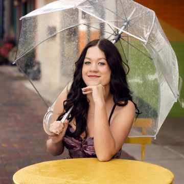 Young woman holding a clear umbrella on a rainy day.