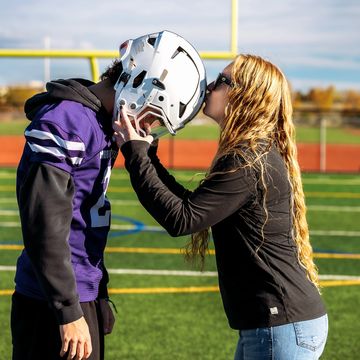 Woman kissing a football player on the helmet.