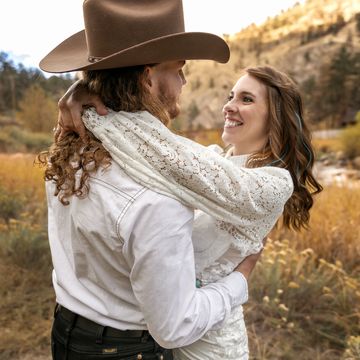 Couple in rustic attire sharing a joyful moment outdoors.