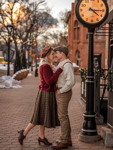 Couple sharing a romantic moment on a sidewalk near a clock.