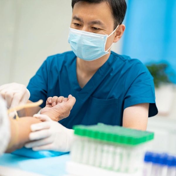 Male nurse in clinic administers blood draw.