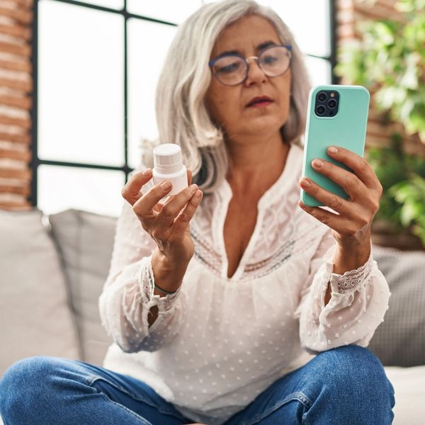 Woman checking her phone app while holding medication