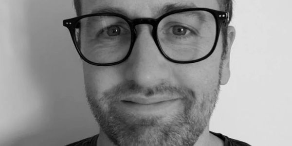 Man with black glasses smiling.