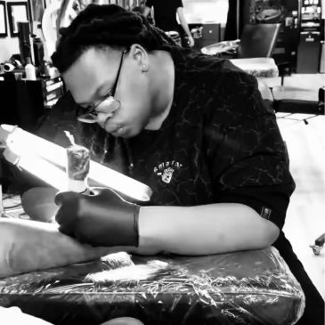 Tattoo artist working on a client's arm in a studio.