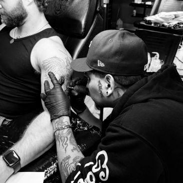 Tattoo artist working on a client's arm.