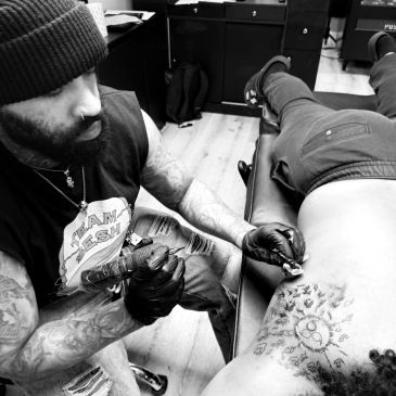 Tattoo artist working on a client's lower back.