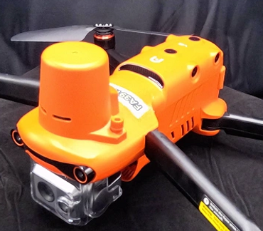 Orange and black quadcopter drone with camera on black cloth.