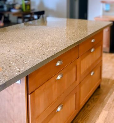 Polished stone countertop with wooden cabinets below in a kitchen.