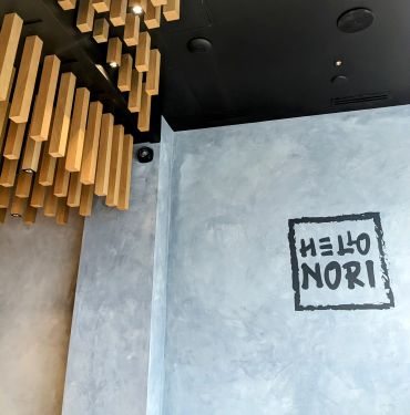 Modern interior with wooden ceiling decor and a wall sign reading 'HELLO NORI'.