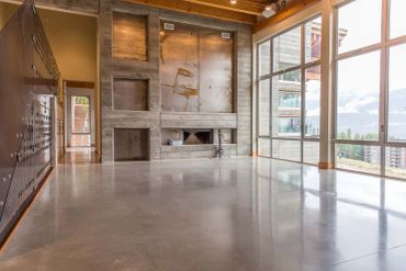 Spacious modern living room with large windows and concrete walls.
