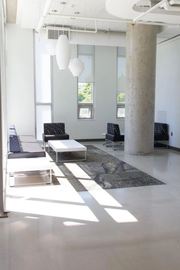 Minimalist waiting area with modern black chairs and white tables.