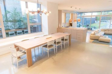 Bright modern dining and living area with large windows and minimalist furniture.
