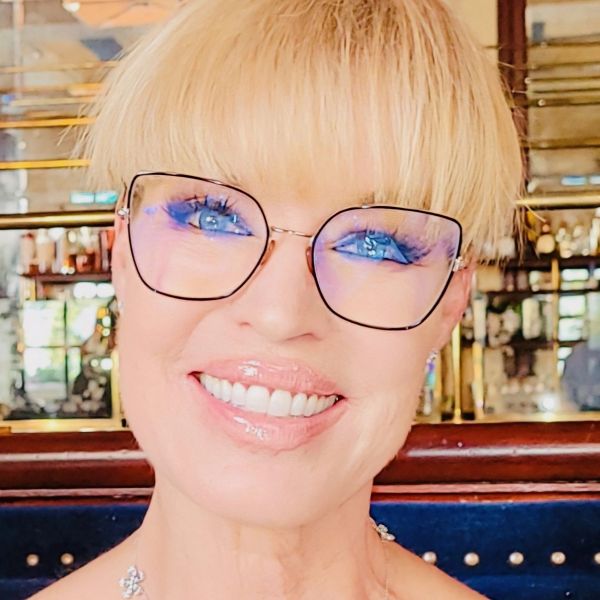 Smiling person with glasses and bright blue eyes.