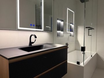 Modern bathroom sink and shower area with minimalistic design.